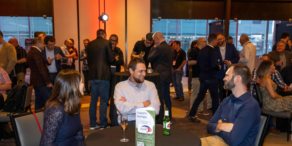 Picture of attendees sitting at a table enjoying some drinks and talking